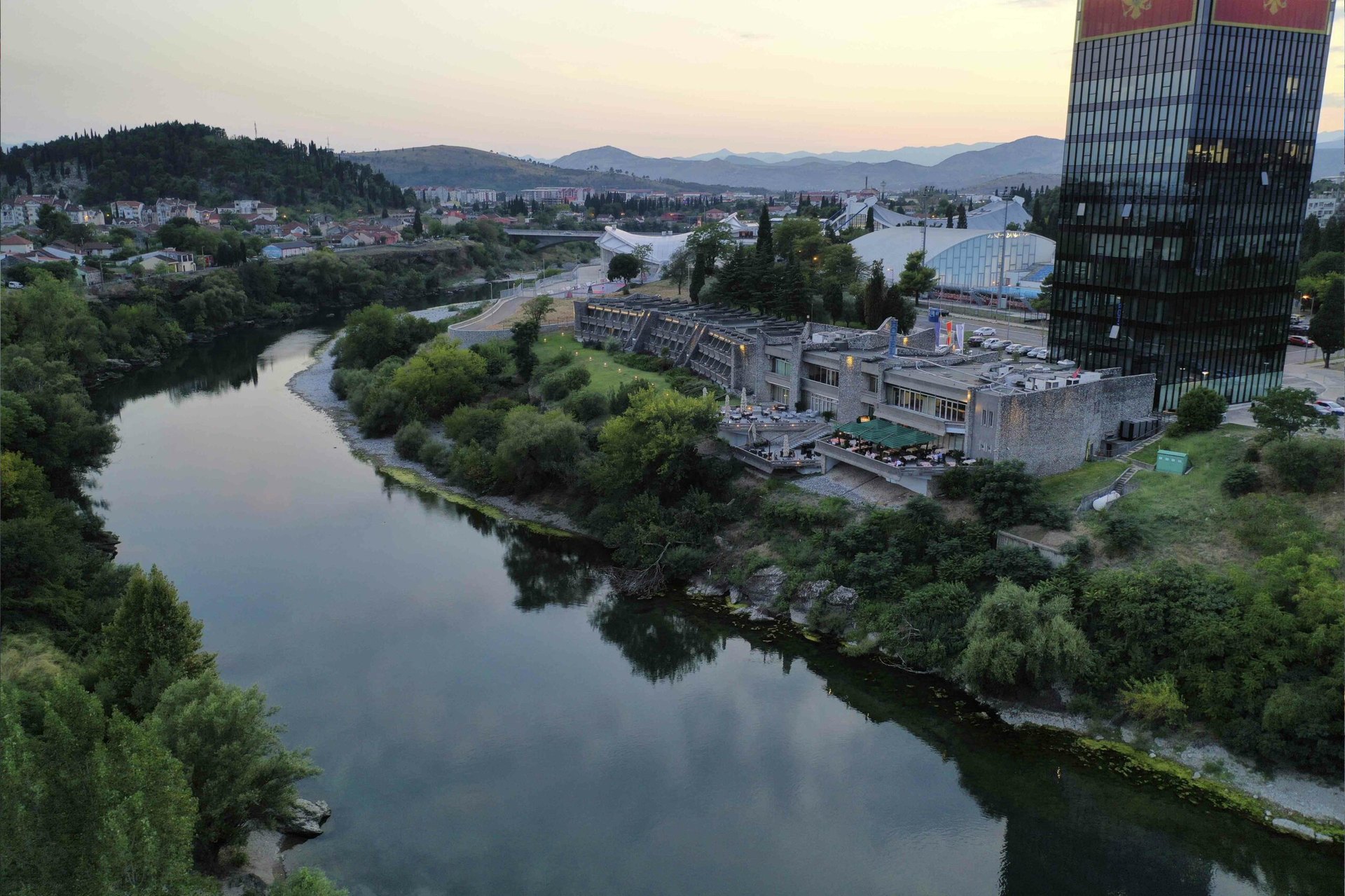 Hotel Podgorica on the bank of the Morača at dusk, seen from above the river